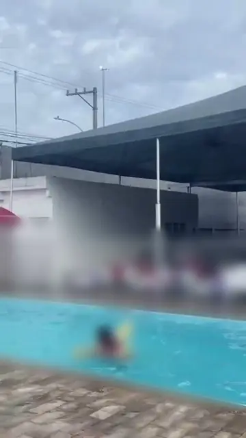 Crianças brincando na piscina de um salão de festas, com macarrões de espuma; os rostos estão desfocados