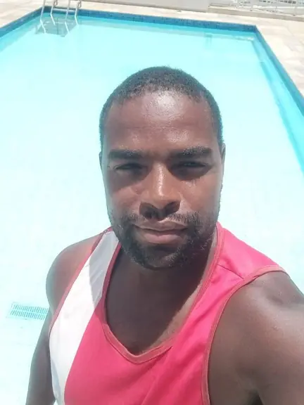 Guarda-vidas de regata vermelha e branca na beira de uma piscina de água azul-clara
